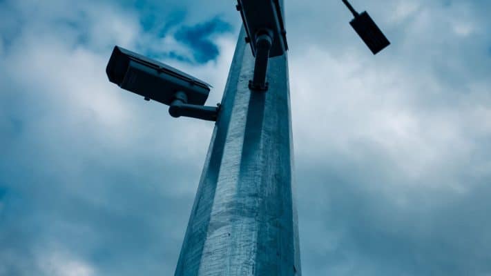 CCTV cameras mounted on a tall pole against a cloudy sky